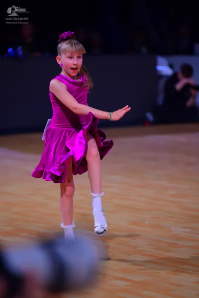 Dancesport competitor: Female dancer: bright pink sleeveless dress with a ruffled skirt made of a shiny