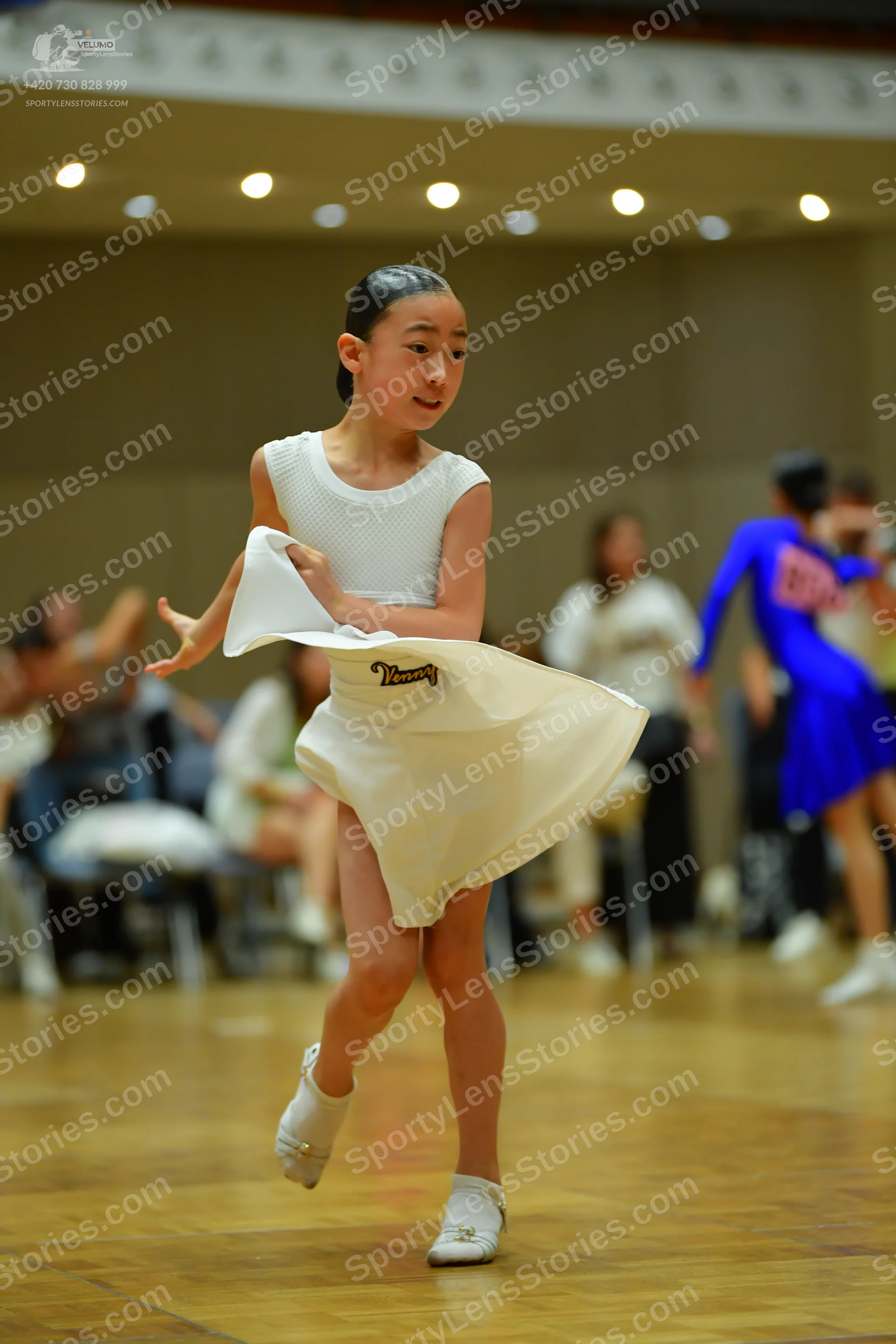 Dancesport competitor: Female dancer in foreground: white sleeveless textured latin dress