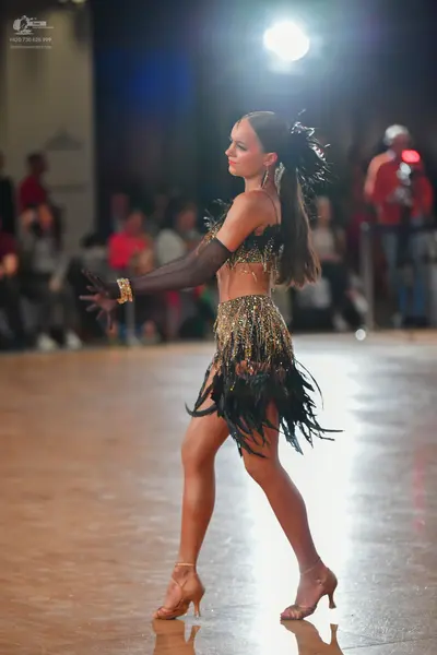Dancesport competitor: Female dancer: black two-piece Latin costume with gold sequin embellishments, fe