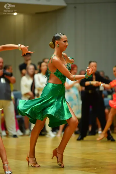 Dancesport competitor: Female dancer: emerald green latin dress with a shimmering fabric, fringe detail