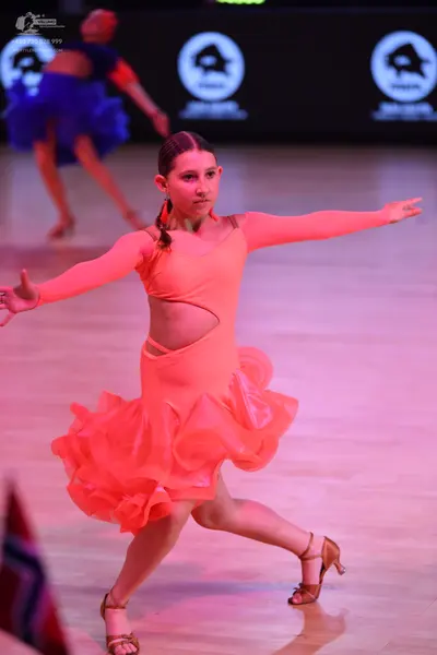 Dancesport competitor: Female dancer (foreground): orange/coral latin dance dress with long sleeves, wa