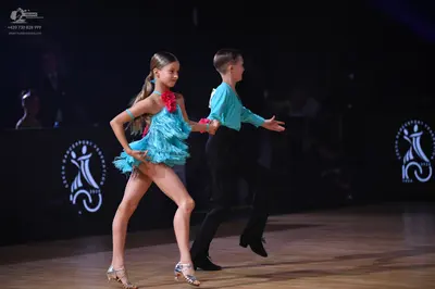 Dancesport competitor: Female dancer: light blue latin dress with fringe and a pink flower accessory on