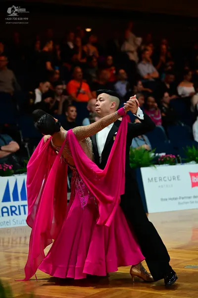 Dancesport competitor: Female dancer: bright pink ballroom gown with a flowing skirt and a sequined bod