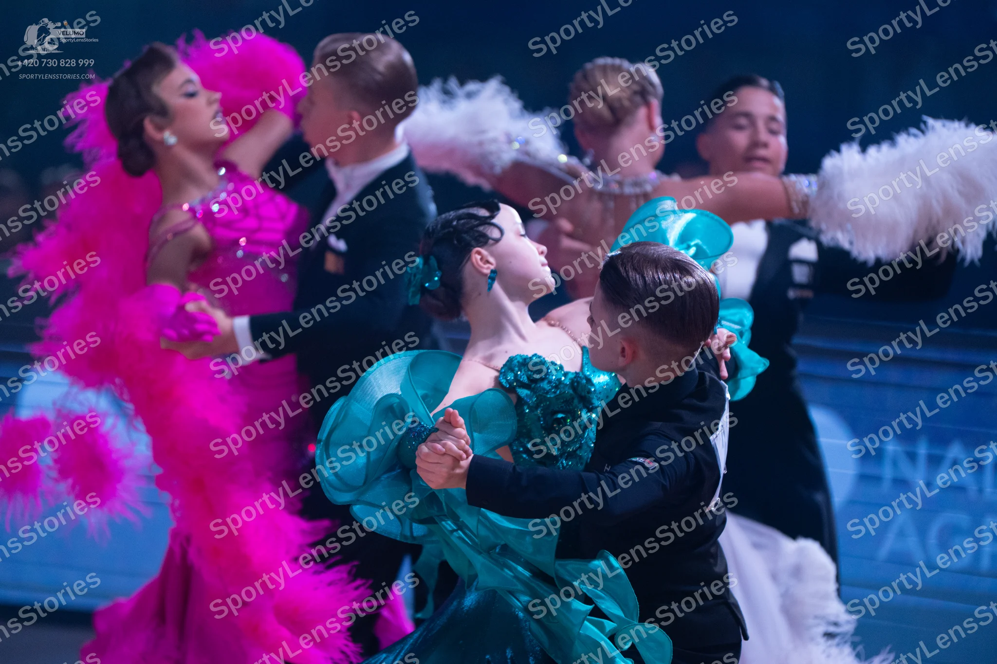 Dancesport competitor: Female dancer (left): bright pink Latin-style dress with large, voluminous pink