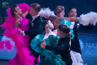Dancesport competitor: Female dancer (left): bright pink Latin-style dress with large, voluminous pink 