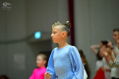 Dancesport competitor: Female dancer in foreground: light blue long-sleeved dress made of smooth fabric