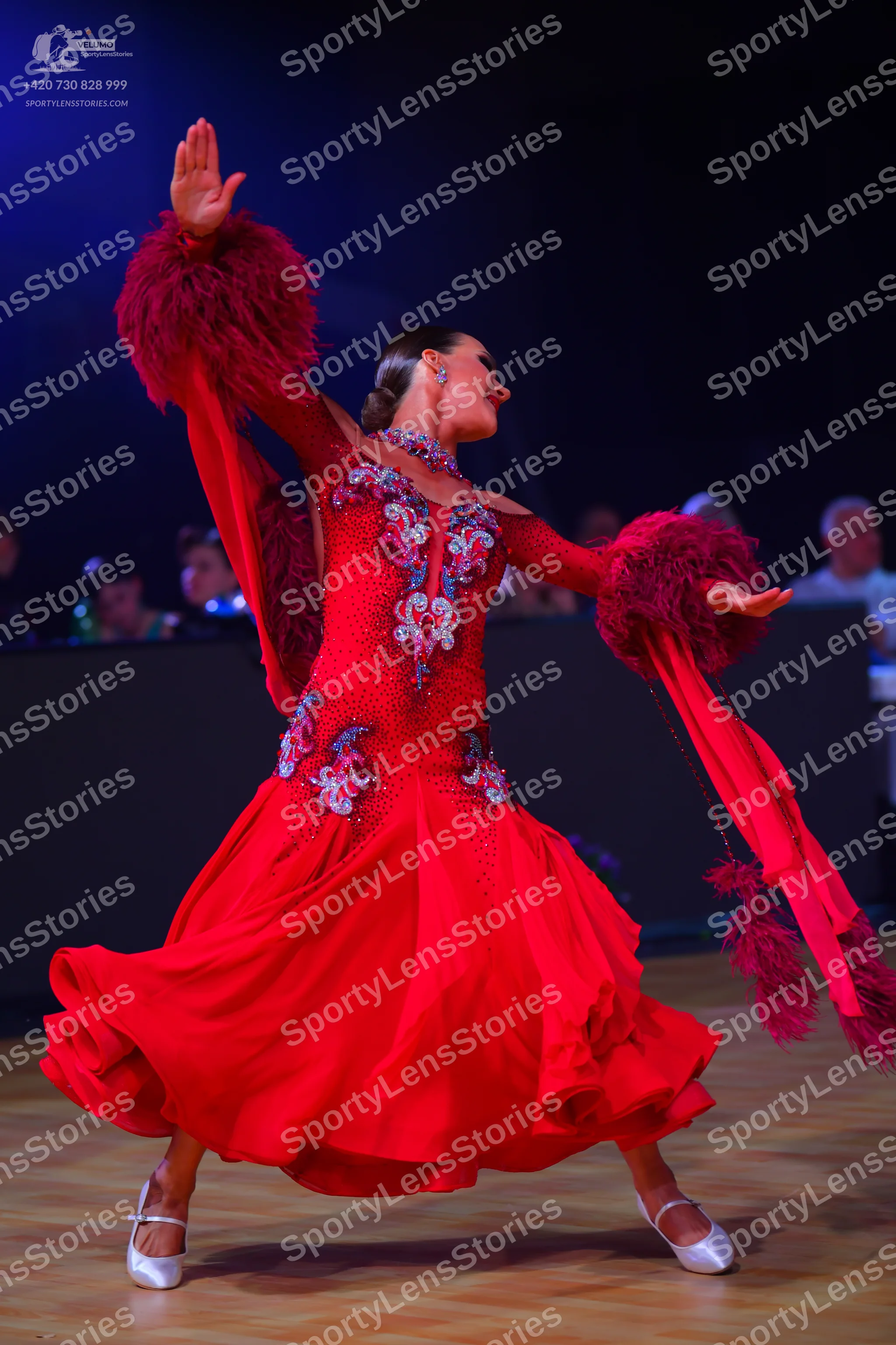 Dancesport competitor: Female dancer: red ballroom dress with long sleeves featuring large red feathere