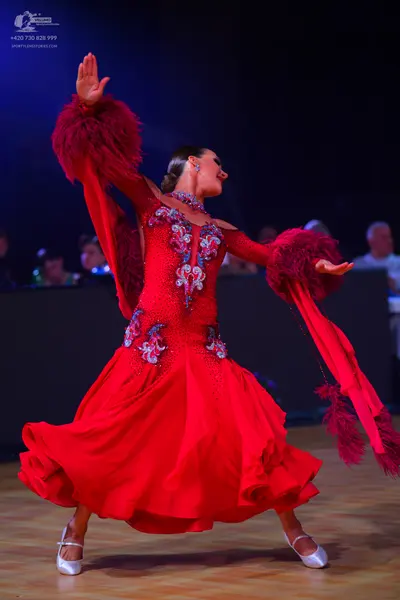 Dancesport competitor: Female dancer: red ballroom dress with long sleeves featuring large red feathere
