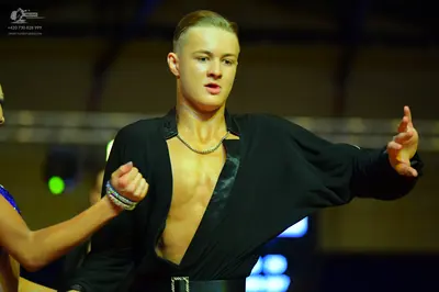 Dancesport competitor: Male dancer: black open-front shirt with satin lapels, a silver chain necklace, 