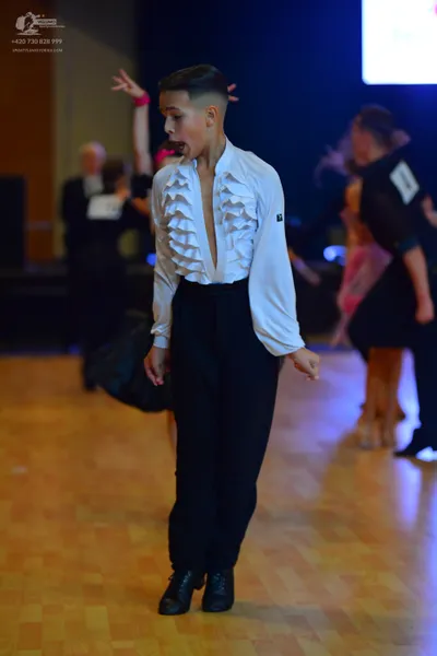 Dancesport competitor: Male dancer (foreground): white long-sleeved shirt with ruffles down the front a