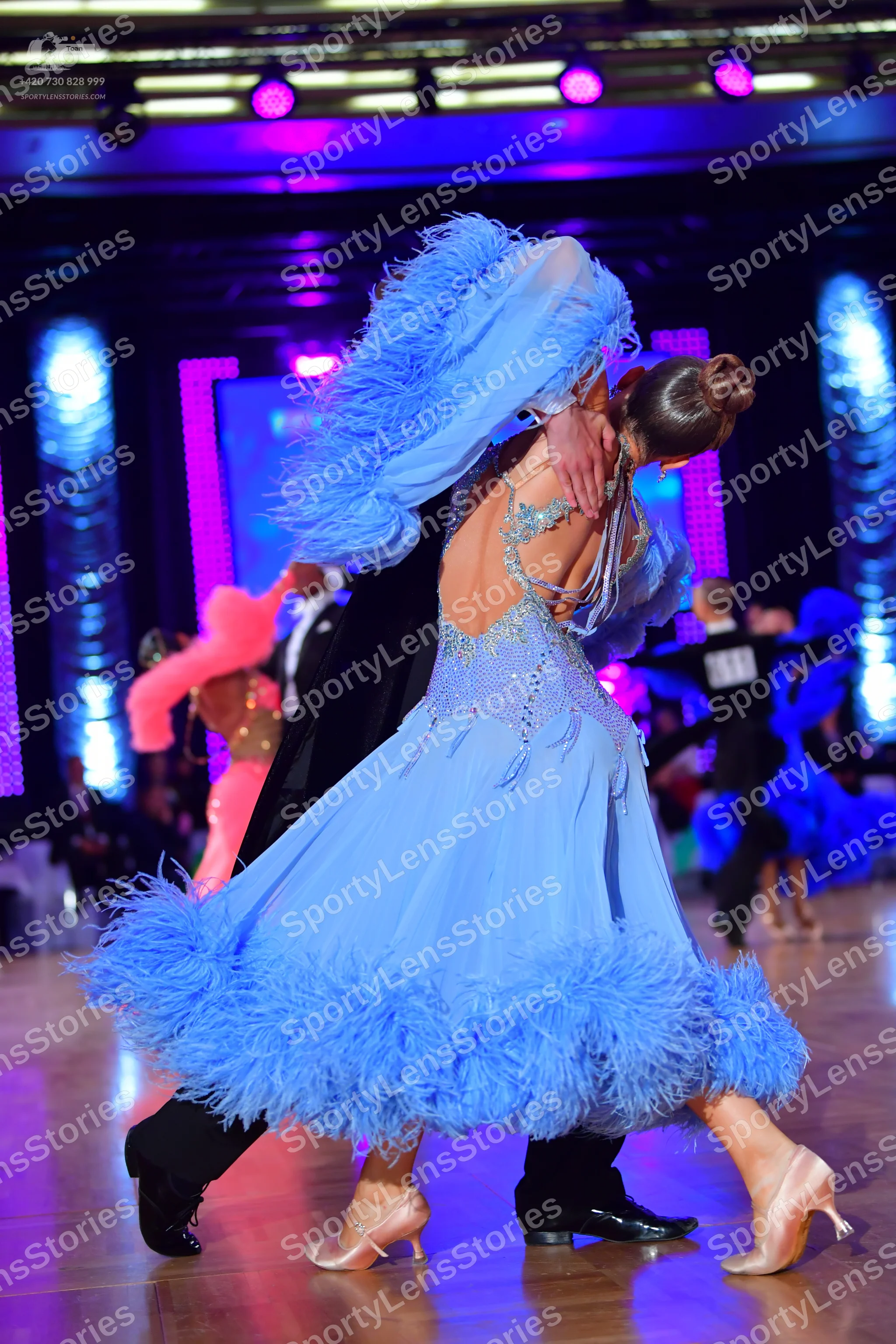 Dancesport competitor: Female dancer: light blue latin dress with extensive feather trim on the hem and