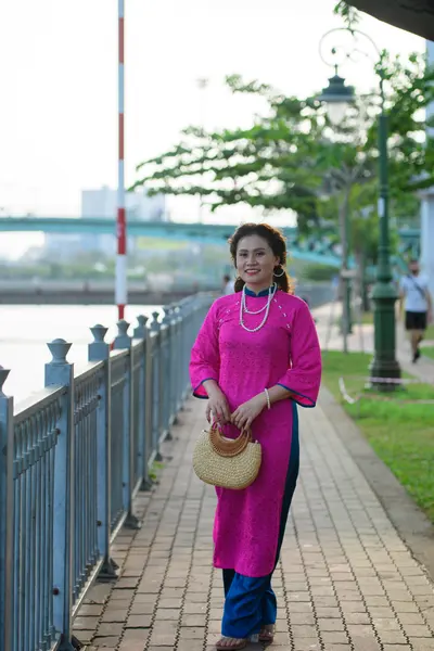 Dancesport competitor: Female dancer: bright pink embroidered long tunic (Áo dài) with blue trousers, p