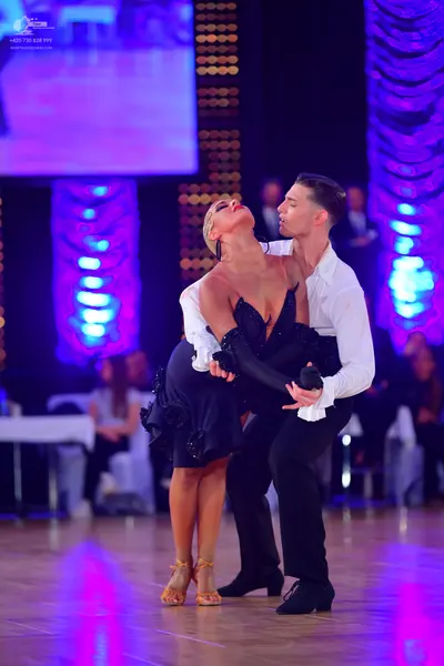 Dancesport competitor: Male dancer: white long-sleeved shirt with ruffled cuffs and black trousers