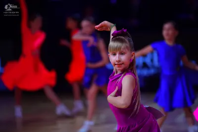 Dancesport competitor: The dancer in the foreground is wearing a magenta sleeveless latin dress with a 