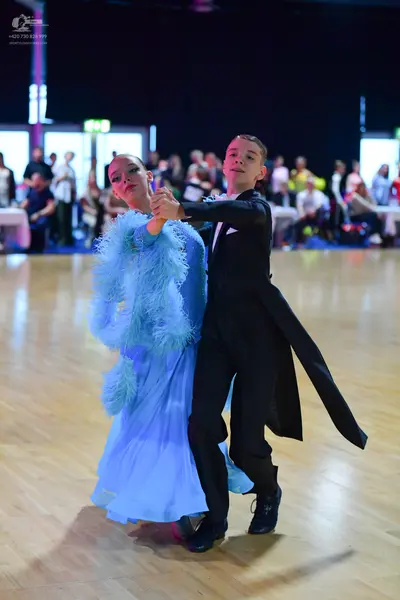 Dancesport competitor: Female dancer: light blue ballroom gown with feathery or ruffled texture on the 
