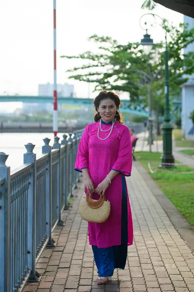 Dancesport competitor: Female subject: magenta-colored traditional Áo dài with blue trousers and subtle