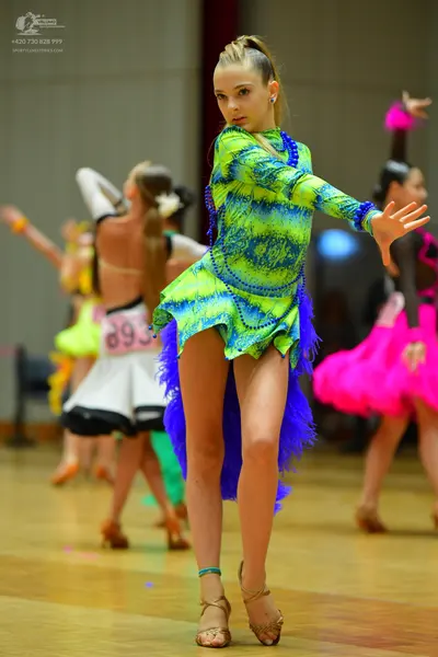 Dancesport competitor #893: Female dancer in foreground: lime green and blue patterned long-sleeved latin dr