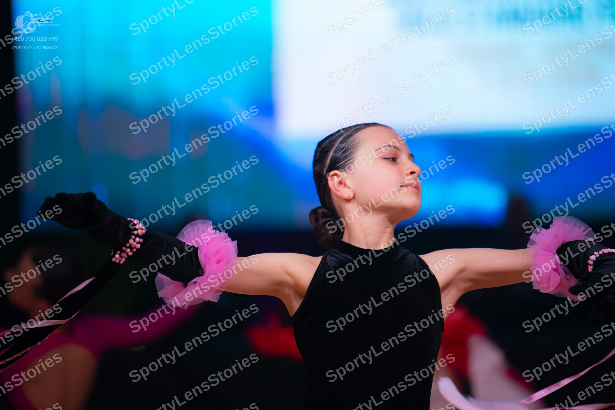 Dancesport competitor: Female dancer: black, long-sleeved, high-neck bodysuit with pink ruffled fabric
