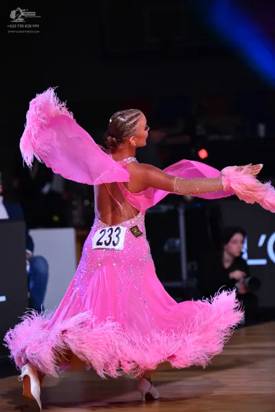 Dancesport competitor: Female dancer: bright pink latin dress with large pink feather trim on the skirt