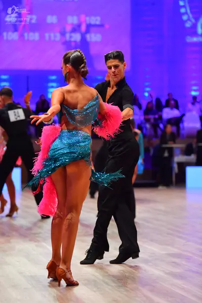 Dancesport competitor: Female dancer: teal sequin Latin dress with pink feather trim