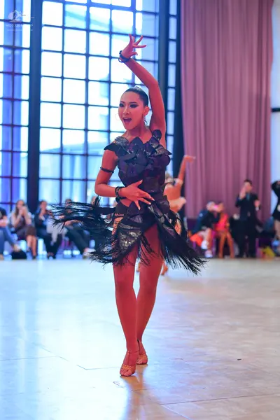 Dancesport competitor: Female dancer in foreground: black Latin dress with a textured bodice and a frin