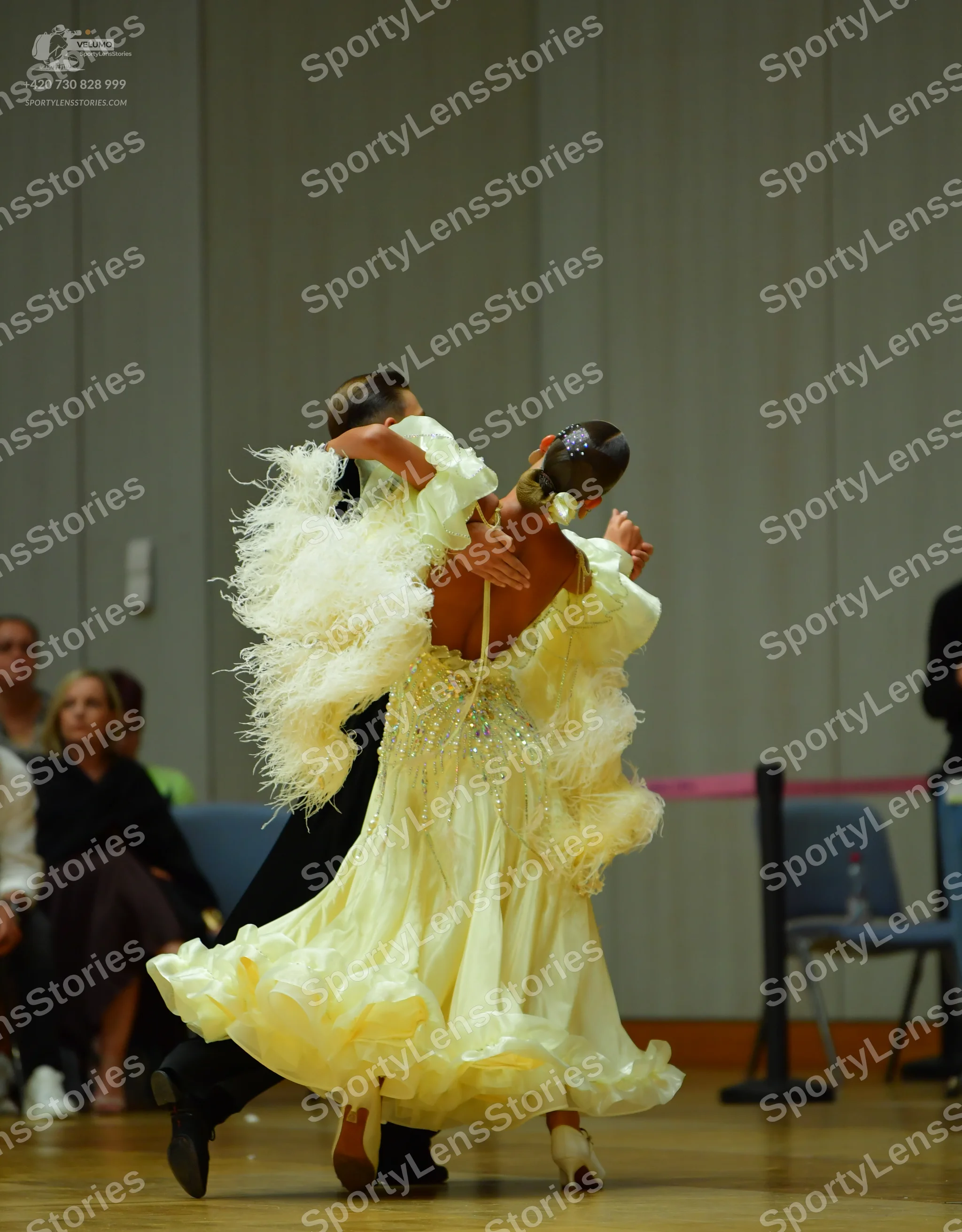 Dancesport competitor: Female dancer: light yellow/cream-colored voluminous ballgown with many ruffled/