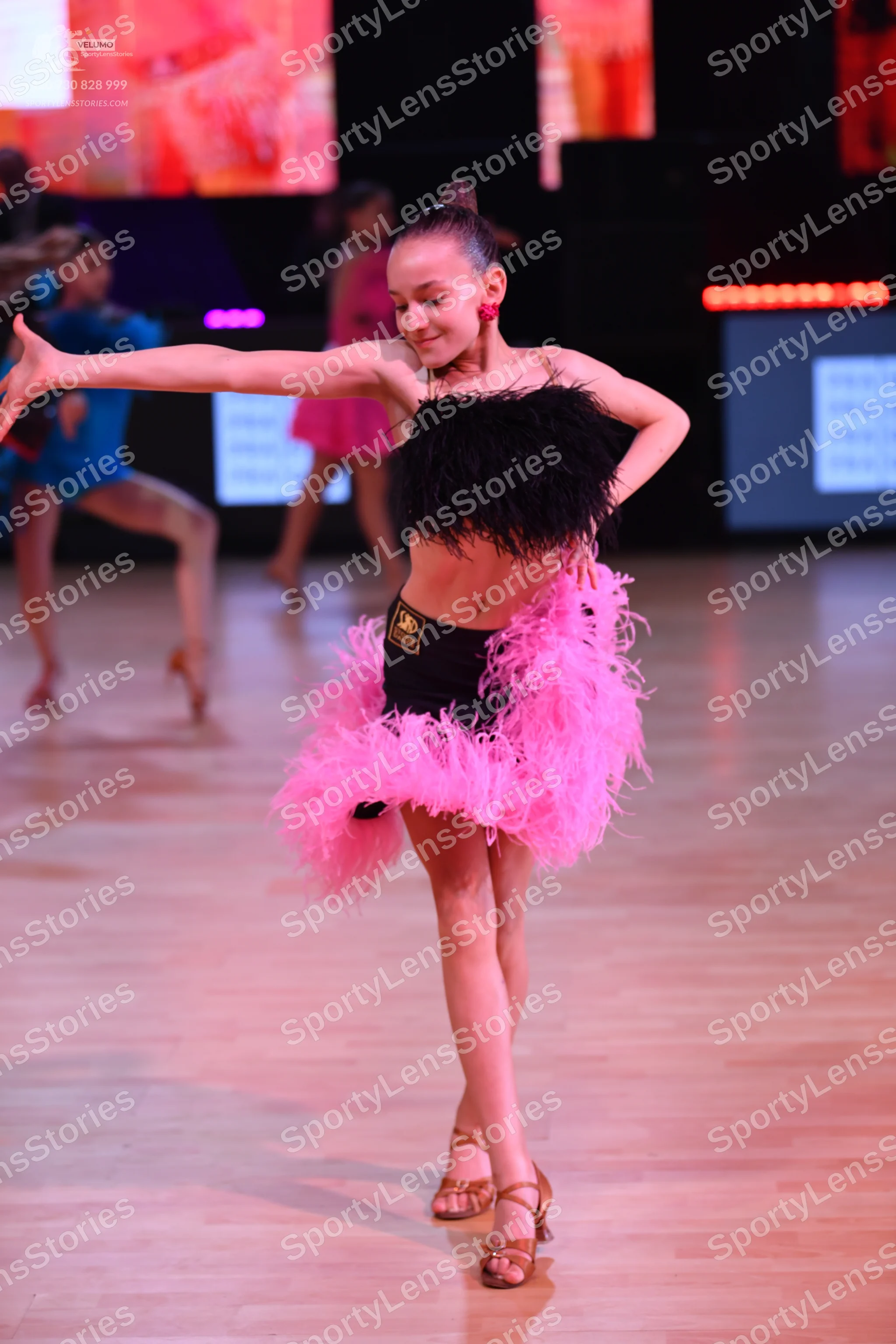 Dancesport competitor: Main dancer: black feathered top with a black high-waisted bottom and a large, v