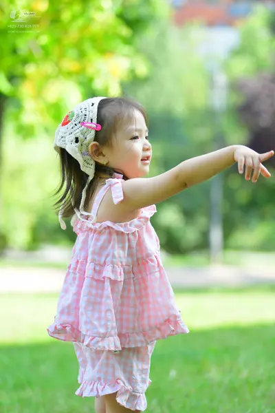 Dancesport competitor: The child is wearing a pink and white gingham patterned sleeveless ruffled top a