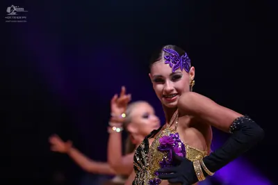 Dancesport competitor: Female dancer (foreground): Gold Latin dance dress with purple sequin/floral emb