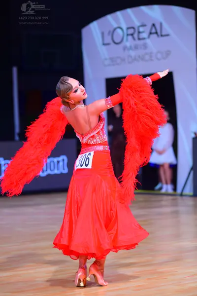Dancesport competitor: Female dancer: red latin dress with sequin bodice and large red feather sleeves