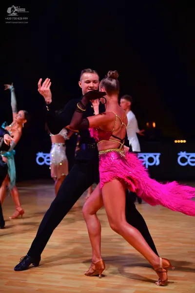 Dancesport competitor: Male dancer (foreground): black long-sleeved shirt and black trousers