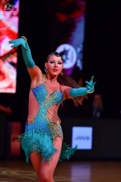 Dancesport competitor: Female dancer: teal Latin dance dress with sequins and fringe, matching long glo