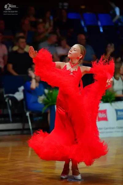 Dancesport competitor: Female dancer: bright red ballroom dress with a voluminous, feathered-style skir