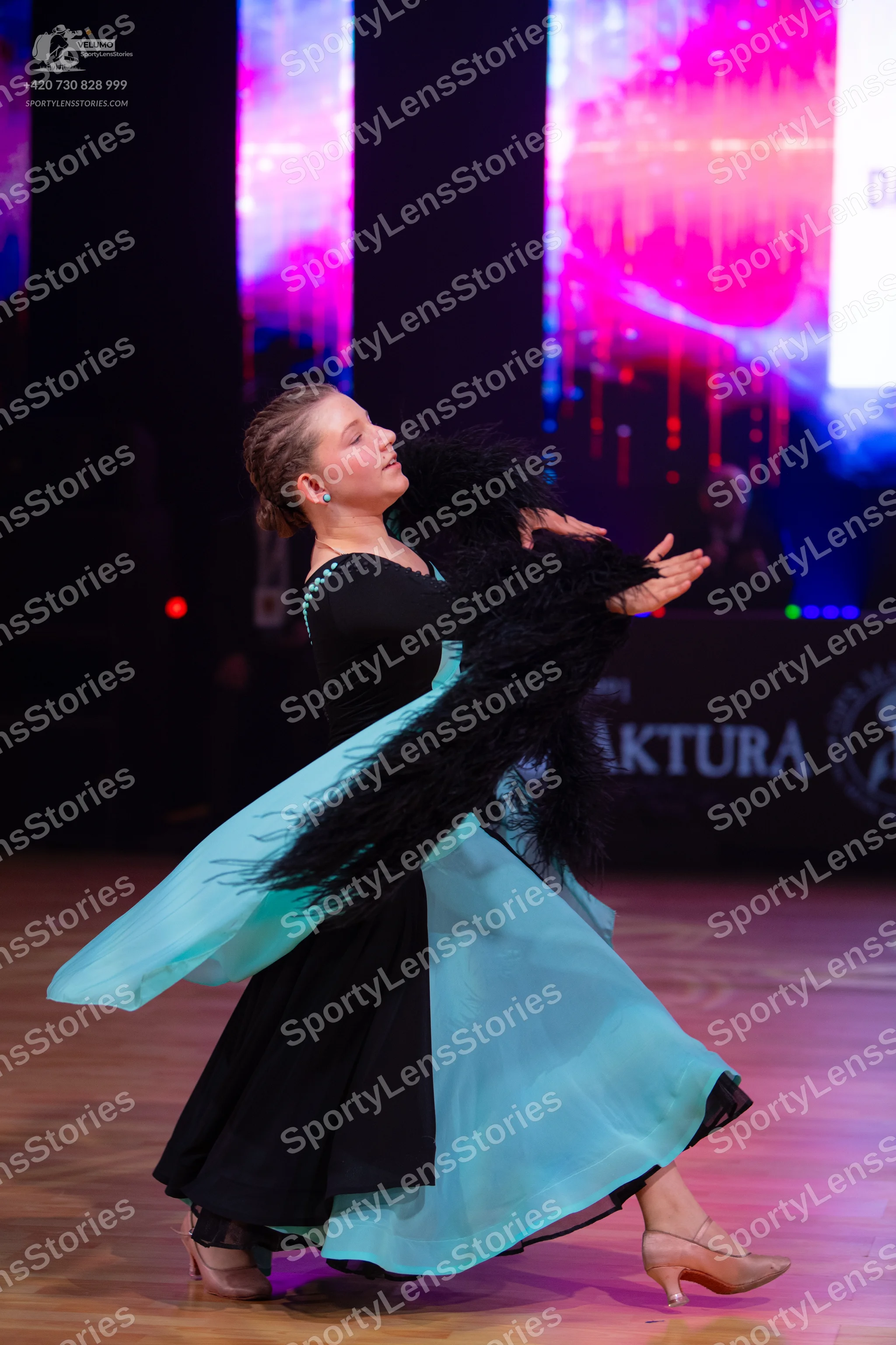 Dancesport competitor: Female dancer: black and light blue ballroom gown with a large, flowing turquois