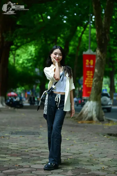 Dancesport competitor: Female dancer: white crop top, cream-colored long-sleeve open shirt, and dark bl