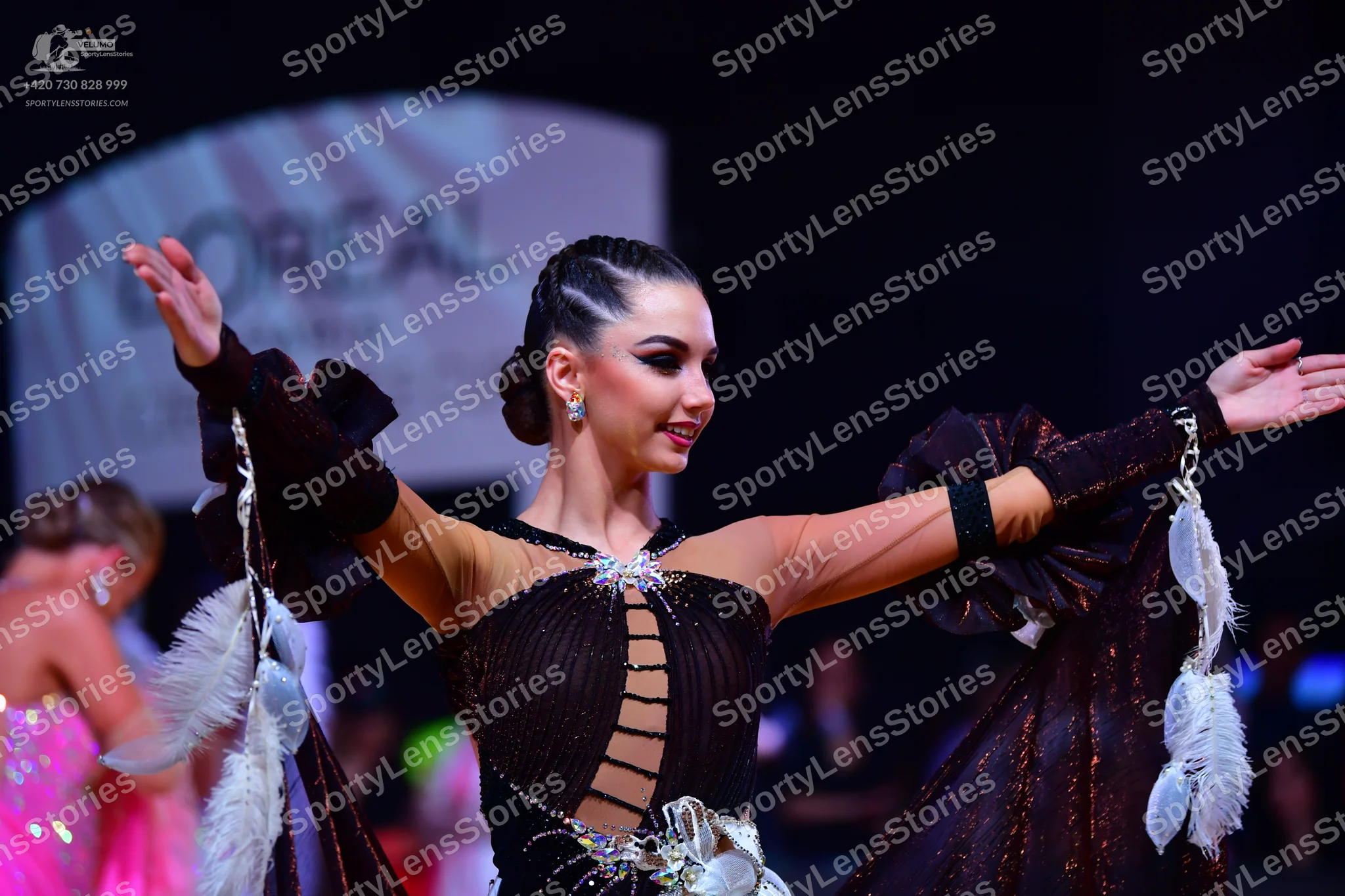Dancesport competitor: Female dancer: dark brown latin dance dress with sheer sleeves, cutouts on the b
