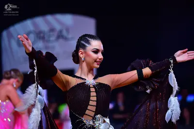 Dancesport competitor: Female dancer: dark brown latin dance dress with sheer sleeves, cutouts on the b
