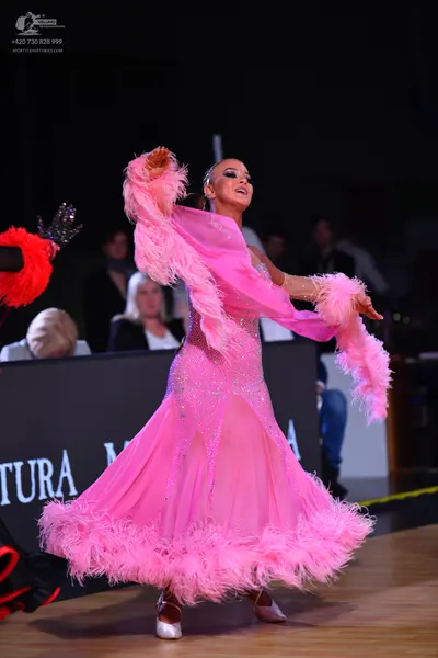 Dancesport competitor: Female dancer: pink ballroom dress with a sequined bodice, sheer skirt, and pink