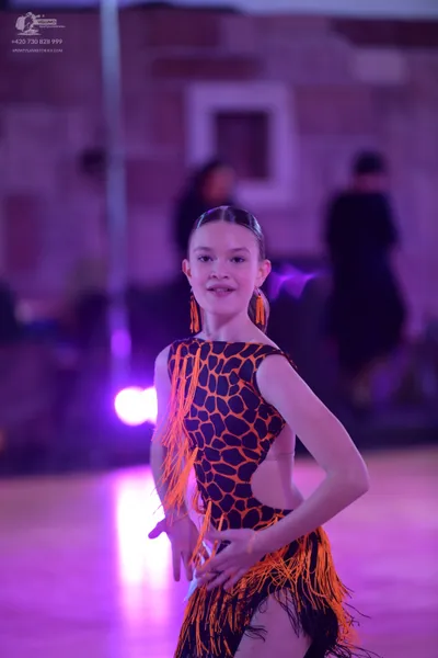 Dancesport competitor: Female dancer: black and orange animal print latin dress with orange fringe and 
