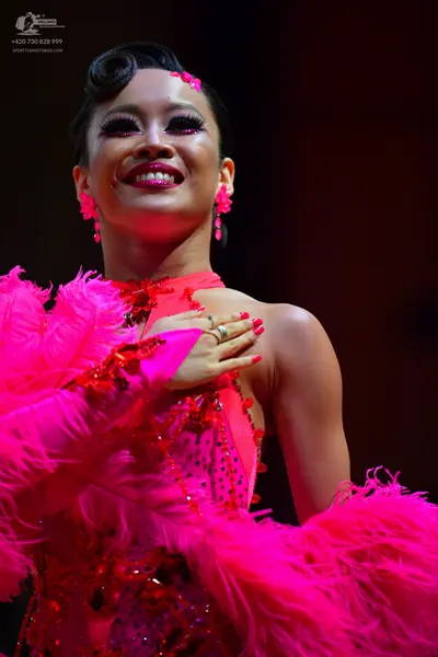 Dancesport competitor: Female dancer: bright pink Latin dance costume featuring sequins and large pink 