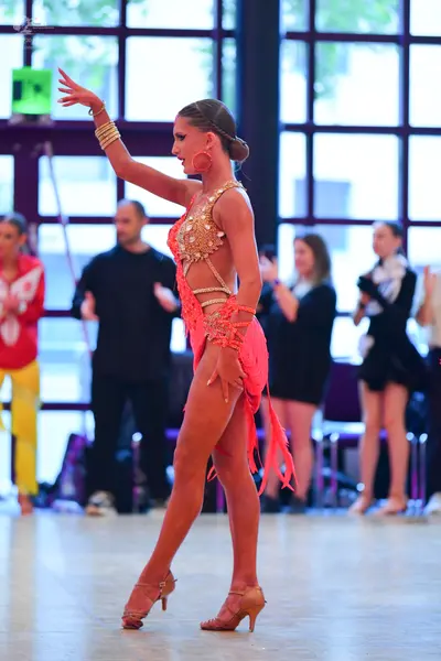 Dancesport competitor: Main dancer: peach-colored Latin dance dress with sequins, cut-outs, and fringe,