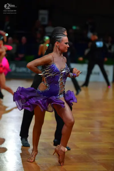 Dancesport competitor: Female dancer: purple latin dress with silver rhinestone embellishments and a ru