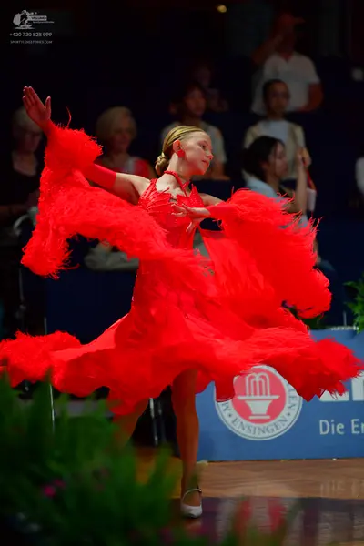 Dancesport competitor: Female dancer: red latin dress with large red feathered skirt and sleeves