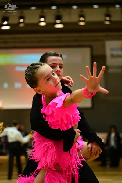 Dancesport competitor: Female dancer: bright pink latin dress with a ruffled bodice and long pink fring