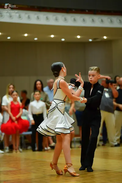 Dancesport competitor: Female dancer: white sleeveless dress with black trim and a flared skirt