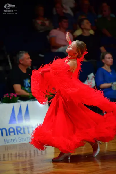 Dancesport competitor: Female dancer: red voluminous ballroom dress made of many layers of red feathers