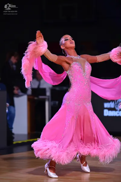 Dancesport competitor: Female dancer: bright pink ballroom dress with a sequined bodice, a flowing shee