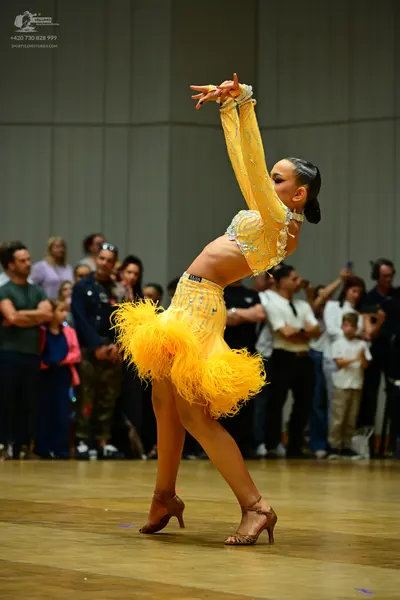 Dancesport competitor: Female dancer: bright yellow latin dance costume featuring a sequined long-sleev