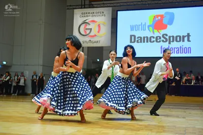 Dancesport competitor: Female dancers: black camisole tops and large, flared navy blue skirts with whit