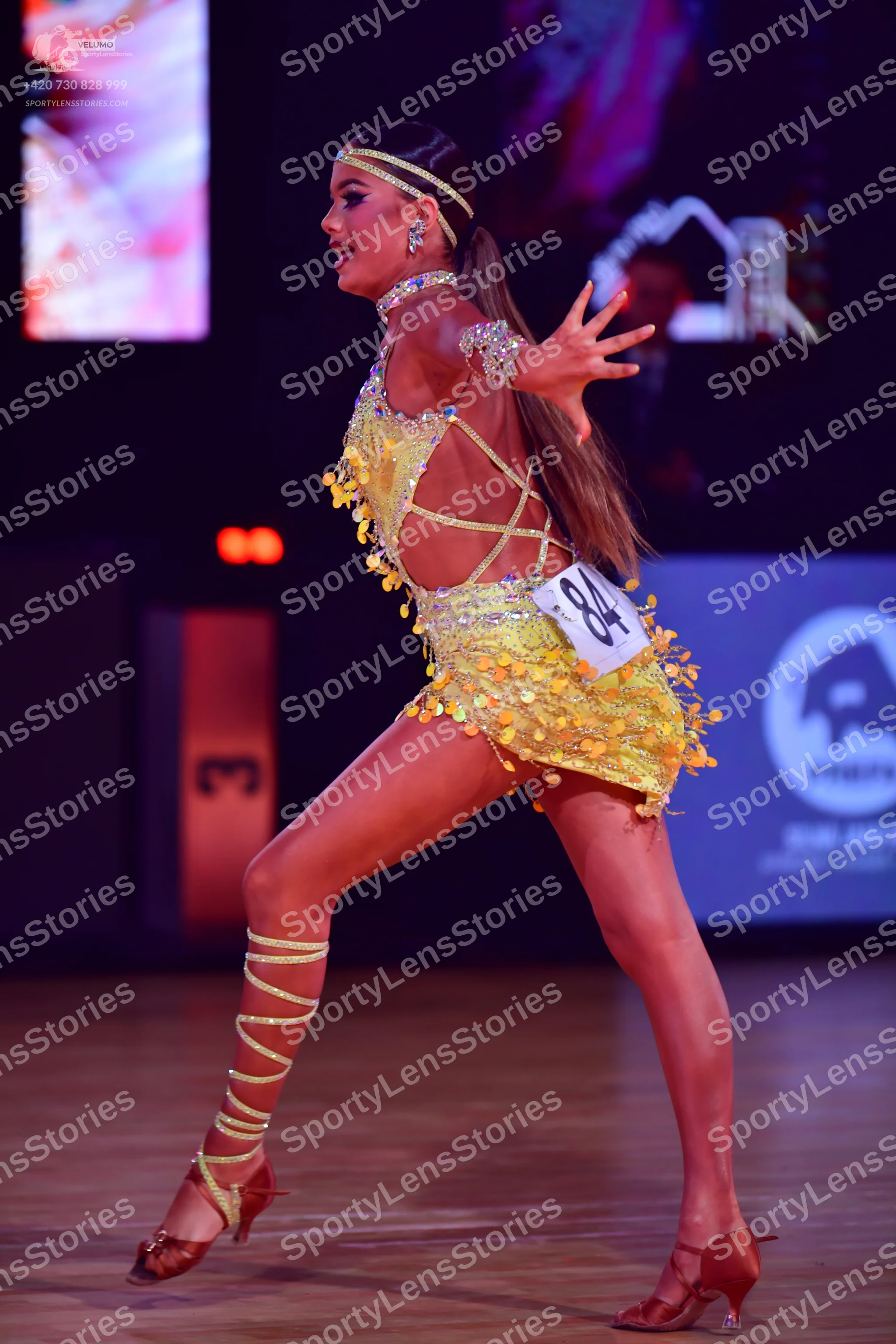 Dancesport competitor: Female dancer: yellow latin dress covered in sequins with petal-like fringe deta